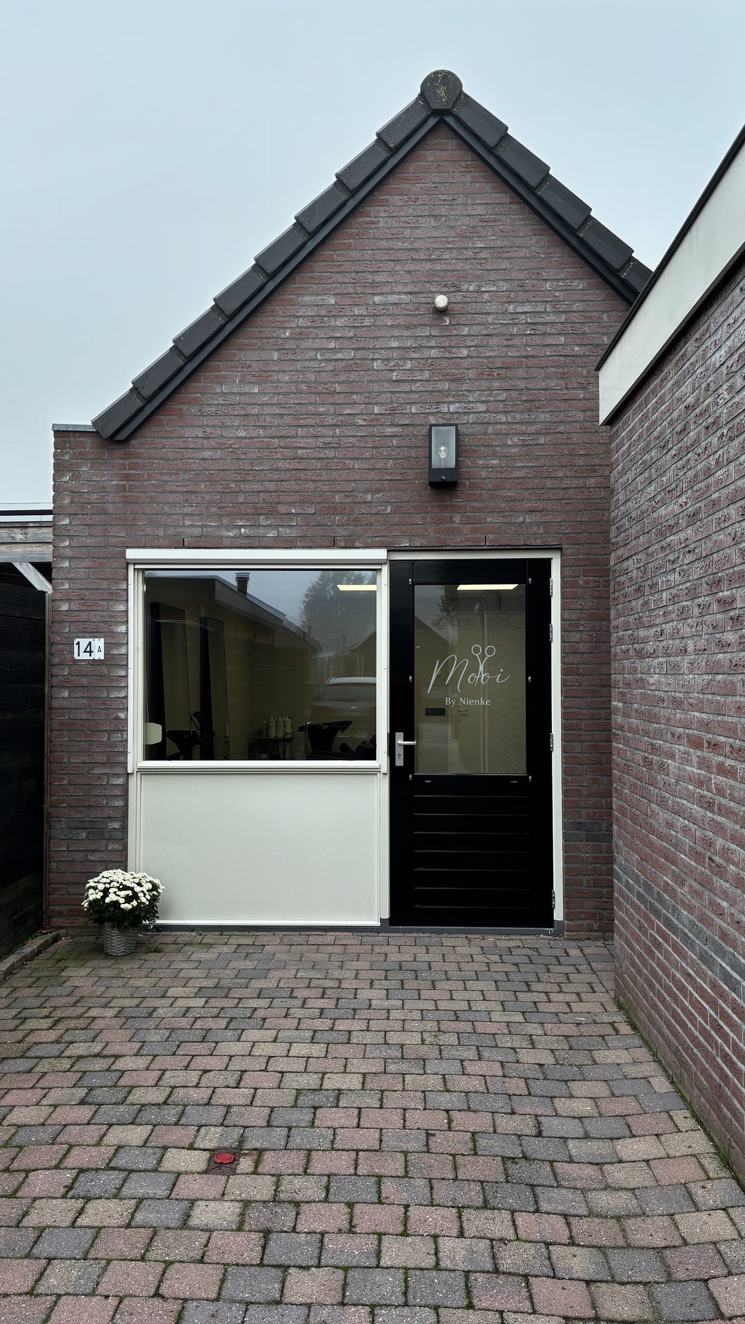 De eigen ingang van de salon: een zwarte deur met het logo van Mooi by Nienke